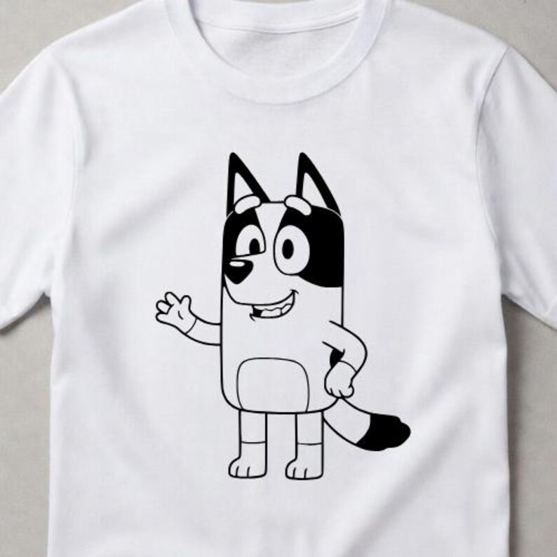 Puede incluir: Una camiseta blanca de manga corta con un gr&aacute;fico de l&iacute;neas negras de un perro de dibujos animados de pie y saludando. El personaje tiene orejas puntiagudas, un hocico redondeado y una cola tupida con manchas negras s&oacute;lidas en las orejas.