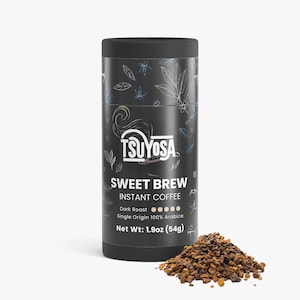 Puede incluir: Un recipiente cilíndrico negro de café instantáneo TSUYOSA Sweet Brew. La etiqueta presenta el texto "SWEET BREW" e "INSTANT COFFEE". Un montón de gránulos de café marrón oscuro está junto al recipiente. Peso neto: 54g.