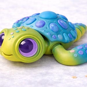 Op de afbeelding: Een speelse speelgoed schildpad in groen, blauw en geel. De schildpad heeft grote, expressieve ogen met paarse irissen en een lachend gezicht. De schild is helderblauw met lichtere blauwe en paarse accenten.