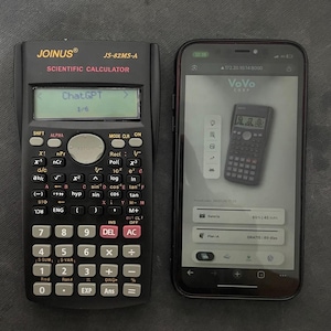 Könnte beinhalten: Ein schwarzer wissenschaftlicher Taschenrechner Joinus JS-82MS-A mit dem Text "ChatGPT" auf dem Display, neben einem Smartphone, das eine Taschenrechner-App anzeigt. Das Telefon zeigt "VoVo Corp" und Batterieinformationen.