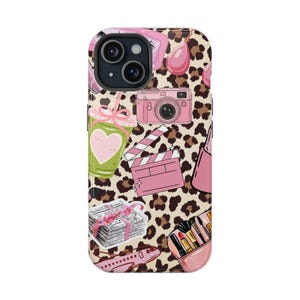 May include: A phone case featuring a leopard print background with pink illustrations. The illustrations include a camera, a film clapperboard, a coffee cup with a heart, a stack of money, a lipstick case, a purse, an airplane, and a pair of earrings.