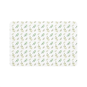 Könnte beinhalten: Eine rechteckige weiße Matte mit einem sich wiederholenden Muster aus grünen und olivgrünen Aquarellblättern. Die Blätter sind diagonal über die Oberfläche der Matte angeordnet.