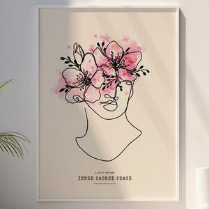May include: A framed art print with a minimalist line drawing of a face adorned with pink and black floral elements. The text "INNER SACRED PEACE" is below the drawing. The artwork is displayed in a bright room with white vases and a potted plant.