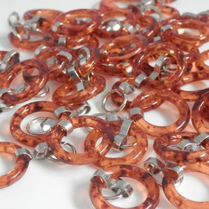 May include: A chain of brown plastic rings with silver metal connectors. The rings are translucent and have a mottled appearance.
