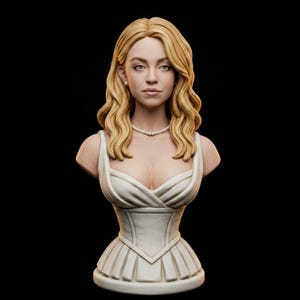 Puede incluir: Escultura de busto detallada de una mujer con largo cabello rubio ondulado, vestida con un vestido blanco y un collar de perlas. La escultura tiene una apariencia realista, con finos detalles en los rasgos faciales y la ropa. El fondo es negro sólido.
