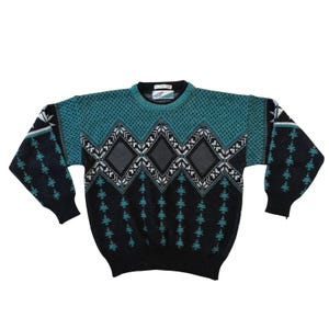 May include: A long-sleeve crew neck sweater featuring a black and teal color scheme. The upper chest has a teal textured knit pattern, while the lower body and sleeves are black with teal tree-like motifs and a central row of diamond shapes.