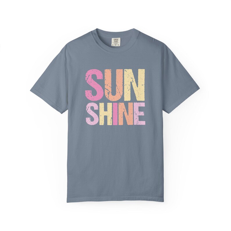 Distressed 'SUNSHINE' graphic tee in blue with pink and orange 'SUN', pink, yellow, and orange 'SHINE' lettering