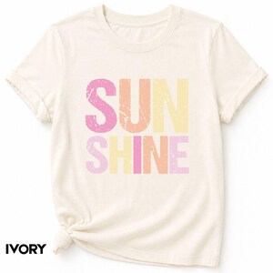 Ivory t-shirt with 'SUNSHINE' graphic in pink, orange, and yellow lettering