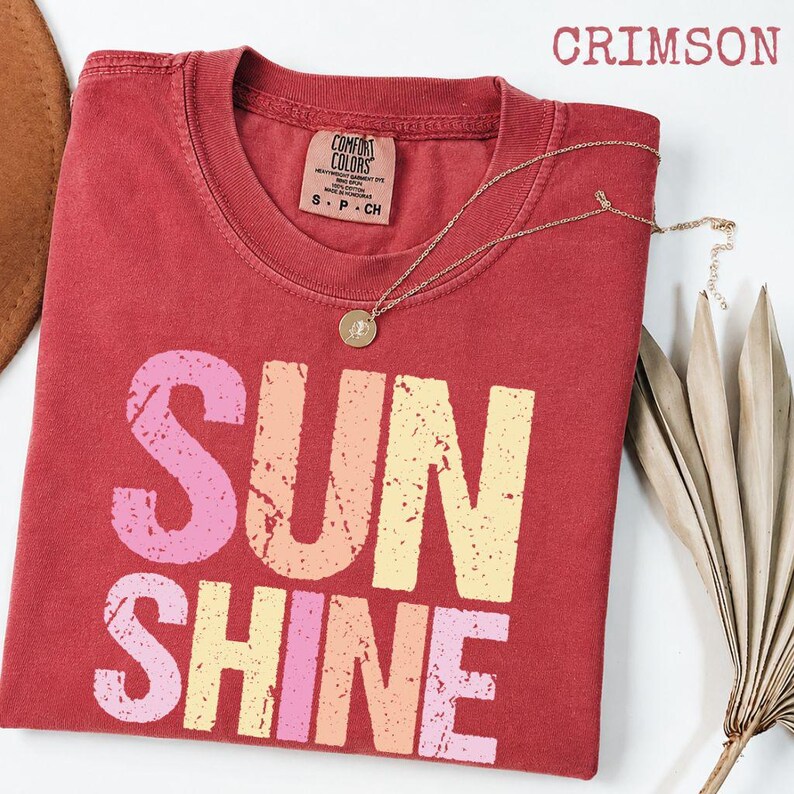 Crimson t-shirt with 'SUNSHINE' graphic in pink, orange, and yellow gradient lettering