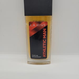 Può includere: Un flacone di profumo rettangolare con tappo nero e corpo in vetro trasparente. L'etichetta recita "LA RIVE ATHLETIC MAN" con accenti rossi e neri. La bottiglia contiene un liquido giallo ed è etichettata "PARFUM DEODORANT".