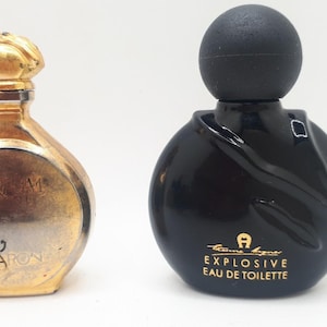 Könnte beinhalten: Zwei Vintage-Parfümflaschen. Eine ist goldfarben mit einem blütenförmigen Verschluss und den Worten "PARFUM" und "CARON" auf der Vorderseite. Die andere ist eine schwarze, runde Flasche mit einem schwarzen, kugelförmigen Verschluss. Der Text "Aigner Explosive Eau de Toilette" ist auf der Vorderseite aufgedruckt.