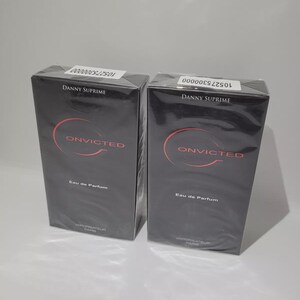 Könnte beinhalten: Zwei schwarze Kartons mit "ONVICTED" Eau de Parfum von Danny Suprime. Die Kartons haben ein rotes kreisförmiges Design und die Wörter "Eau de Parfum" und "Vaporisateur Paris" sind aufgedruckt.