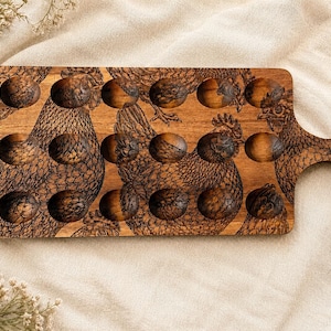 May include: A rectangular wooden egg holder tray featuring a laser-engraved pattern of chickens across the surface. The tray includes eighteen circular indentations for eggs, a handle on the right side, and a piece of twine attached for hanging.