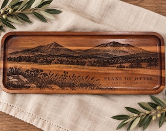 May include: A rectangular wooden tray featuring a laser-engraved landscape of the Peaks of Otter in Bedford, Virginia. The design depicts mountain peaks, a forest, and foreground wildflowers. The text reads PEAKS OF OTTER BEDFORD VIRGINIA.