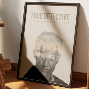 May include: Framed poster featuring the text "TRUE DETECTIVE" above the names Matthew McConaughey and Woody Harrelson. The poster has a black frame and a beige background. The image inside the frame is a grayscale portrait of a man with an overlay of power lines and a cloudy sky.
