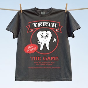 Funny Widow's Bay tv show t-shirt with Teeth board game graphic on a unisex washed black comfort colors graphic tee