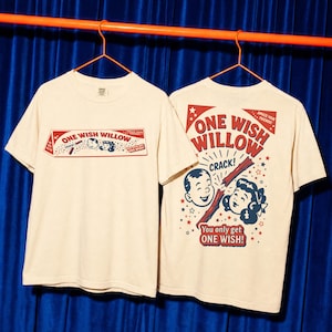 Könnte beinhalten: Ein cremefarbenes Kurzarm-T-Shirt mit einem roten und blauen Grafikdruck. Die Vorderseite zeigt ein rechteckiges Kastendesign mit dem Text ONE WISH WILLOW. Die Rückseite zeigt eine größere Version derselben Grafik mit einem gebrochenen Ast.