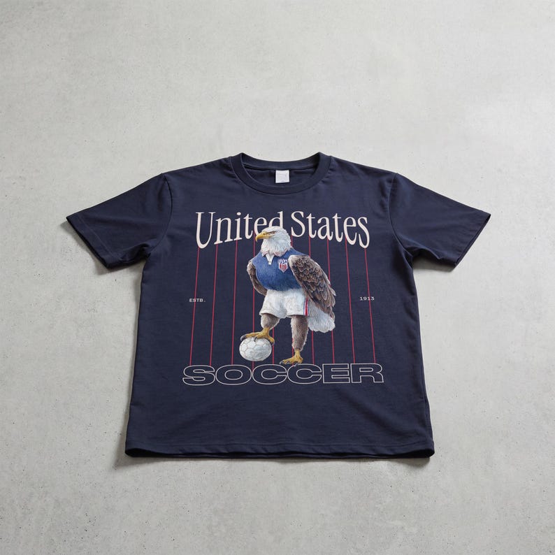 Vintage USMNT soccer fan graphic t-shirt with bald eagle soccer player and pinstripes on a navy graphic tee of USA world cup soccer fans