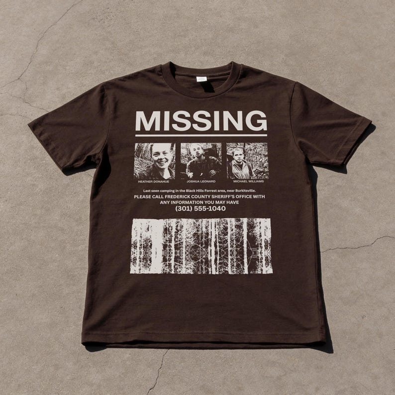 May include: A brown t-shirt with the word "MISSING" in white block letters. Below are three small black and white photos of people. Underneath the photos is text that reads "PLEASE CALL FREDERICK COUNTY SHERIFF'S OFFICE WITH ANY INFORMATION YOU MAY HAVE (301) 555-1040."