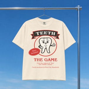 Funny Widow's Bay tv show t-shirt with Teeth board game graphic on a unisex washed cream off white comfort colors graphic tee