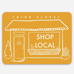 May include: A yellow illustration of a storefront with the text "Think Global Shop Local" above the door. The door has a sign that says "Open". There are plants in a window box and a potted plant outside.