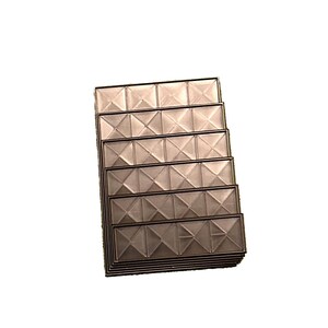 May include: A stack of rectangular, metallic-looking tiles with a geometric, diamond-like pattern. The tiles are arranged in a slightly angled stack, showcasing their textured surface and reflective quality. The color is a muted, neutral tone.
