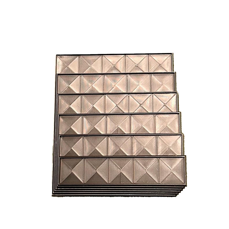May include: A stack of rectangular, textured panels with a repeating diamond pattern. The panels have a metallic sheen and are framed with a dark border. The design creates a geometric and dimensional effect.