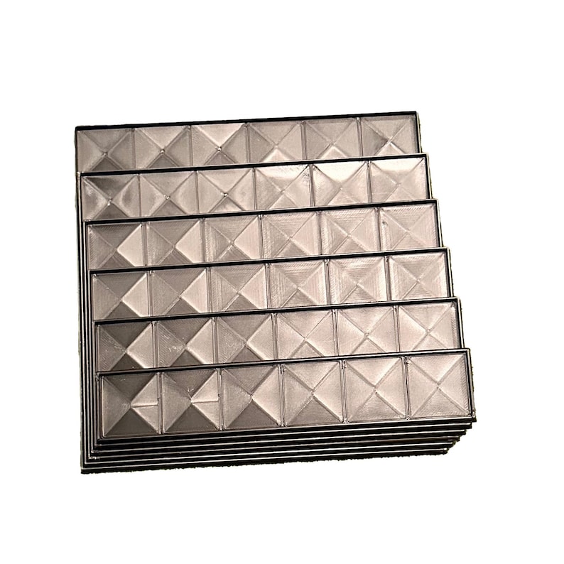 May include: A stack of clear, rectangular trays with a geometric, diamond-like pattern. Each tray is outlined with a thin, black border. The trays are stacked on top of each other, creating a tiered effect. The overall color is a neutral, translucent gray.