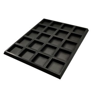 May include: A black, rectangular tray with a grid of 20 square compartments. The tray has a textured surface and raised edges. The compartments are evenly spaced and appear to be designed to hold small items. The tray is made of a solid, dark material.