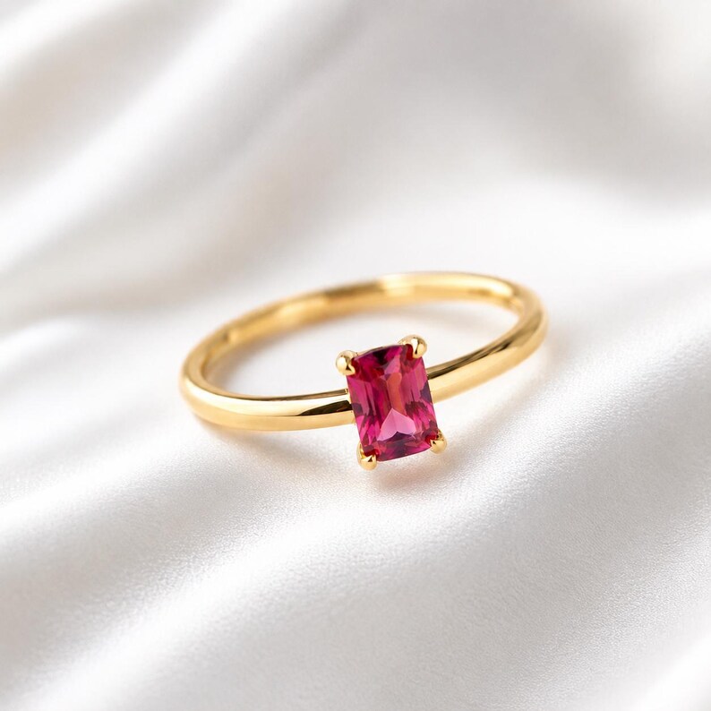Minimalist pink ruby gemstone 925 sterling silver gold plated ring displayed on elegant white satin fabric with a softly blurred background.