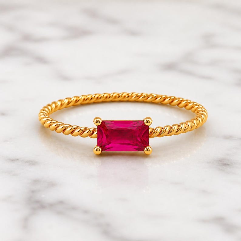 925 Sterling Silver Gold Plated Ruby gemstone ring with twisted gold band displayed on soft white marble, focused closely on the jewelry.