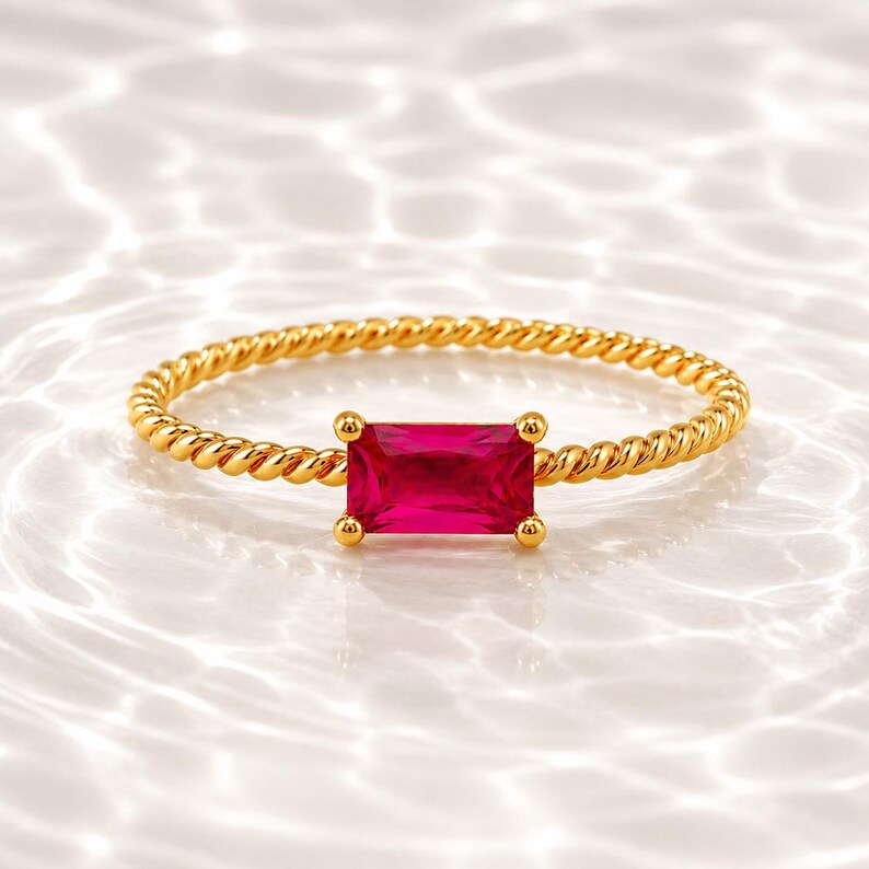 925 Sterling Silver Gold Plated Ruby gemstone ring with horizontal stone and twisted gold band displayed on a soft white water ripple surface.