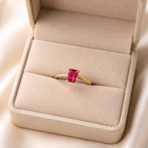 Pink emerald ruby gemstone solitaire ring in 925 sterling silver gold plated displayed in a soft champagne beige velvet jewelry box.