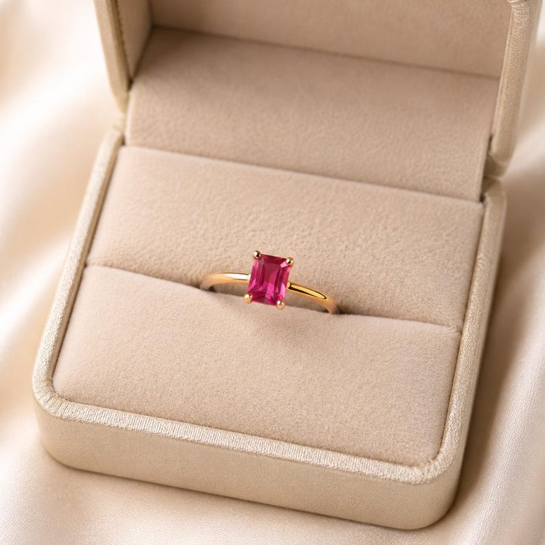Pink emerald ruby gemstone solitaire ring in 925 sterling silver gold plated displayed in a soft champagne beige velvet jewelry box.