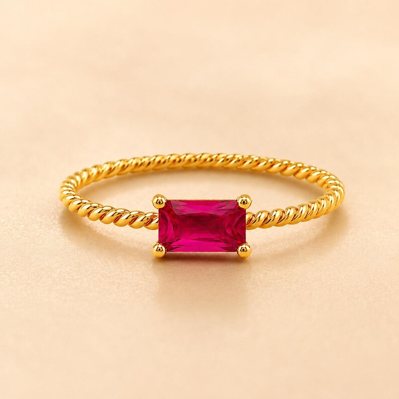 925 Sterling Silver Gold Plated Ruby statement ring with horizontal gemstone and twisted gold band on a warm champagne beige surface.