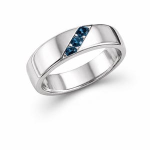 Könnte beinhalten: Ein polierter Ring aus silberfarbenem Metall mit einer diagonalen Fassung, in der drei kleine, runde, dunkelblaue Edelsteine sitzen. Der Ring hat eine glatte, reflektierende Oberfläche und eine breite, solide Konstruktion.