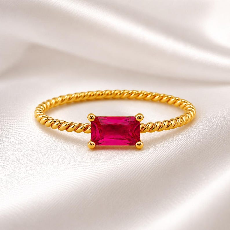 925 Sterling Silver Gold Plated Ruby ring with twisted gold band resting on elegant white satin, showing the gemstone and setting in sharp detail.