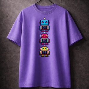 Puede incluir: Una camiseta morada con un diseño de cuatro ilustraciones de robots coloridos apilados verticalmente. Cada robot tiene un esquema de color diferente y muestra un número binario: 01, 10 y 11. La camiseta está colgada de una percha negra.