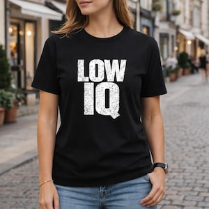 Può includere: T-shirt nero girocollo con la scritta "LOW IQ" in lettere bianche invecchiate. Uno stile casual, adatto all'uso quotidiano.