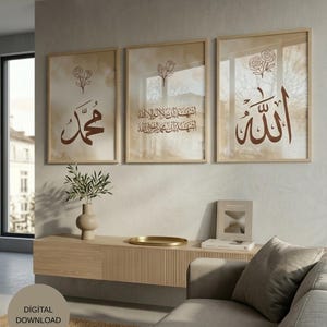May include: Three framed art prints with Arabic calligraphy in brown against a beige background. Each print features a different inscription and a floral design. The frames are light brown, and the overall aesthetic is minimalist and elegant.