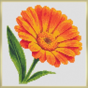 May include: A cross-stitch depiction of a bright orange and yellow gerbera daisy with a brown centre. The flower features detailed petals and is accompanied by a green stem and leaves. The artwork is framed within a gold-coloured border.