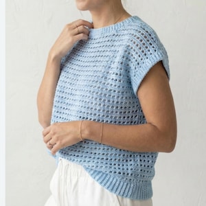 Puede incluir: Un top de crochet azul claro con cuello redondo y mangas cortas. El dise&ntilde;o de tejido abierto crea un aspecto aireado y transpirable. El top es de color liso y parece hecho a mano. El dobladillo inferior y los pu&ntilde;os de las mangas tienen una textura acanalada.