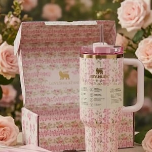 May include: A floral-patterned Stanley Loveshackfancy tumbler with a pink lid and handle, presented with a matching box and straw. The tumbler features the Stanley and Loveshackfancy logos. The design includes pink and white flowers.