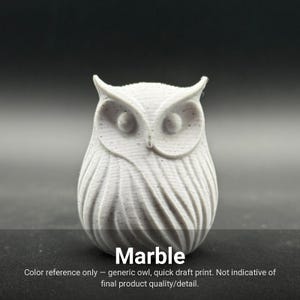 May include: A light gray owl figurine with subtle dark speckles throughout its surface. The owl features prominent ear tufts, circular eyes, and vertical textured lines representing feathers. The text "Marble" is printed at the bottom.