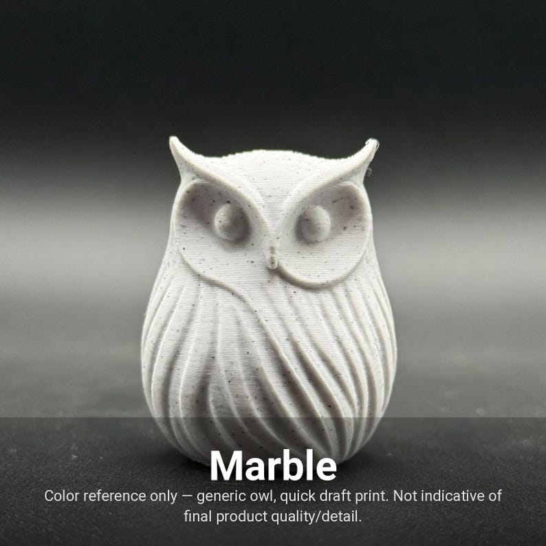 May include: A light gray owl figurine with subtle dark speckles throughout its surface. The owl features prominent ear tufts, circular eyes, and vertical textured lines representing feathers. The text "Marble" is printed at the bottom.