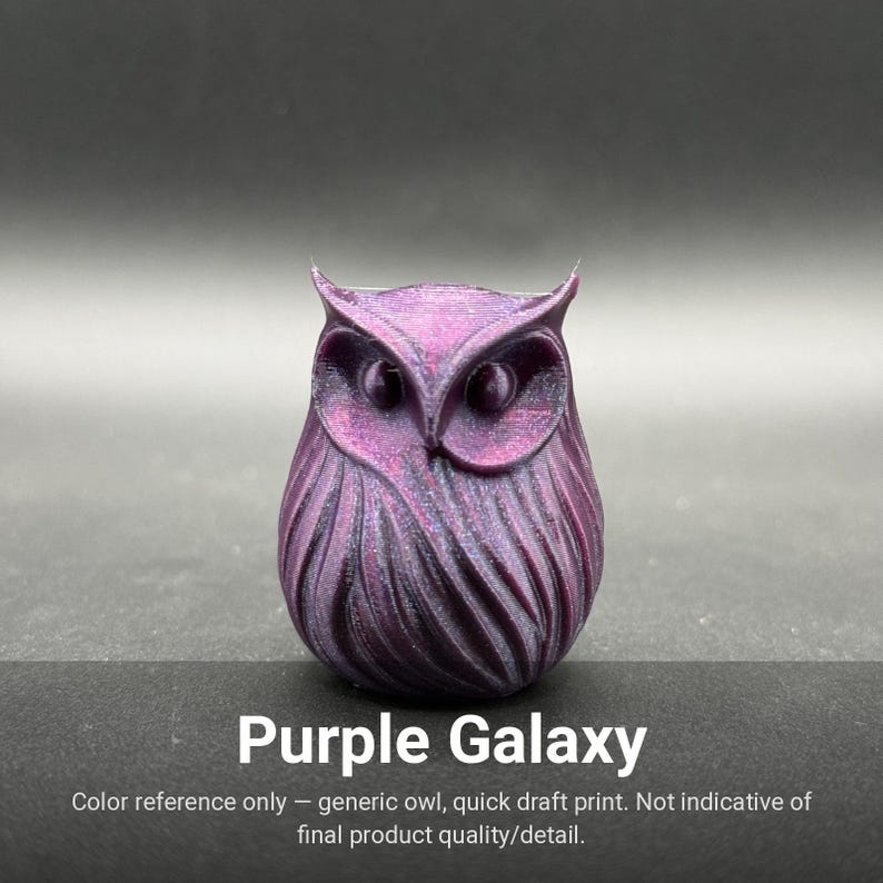 May include: A small, stylized owl figurine featuring a deep purple and black iridescent finish with a textured, layered feather pattern. The object displays prominent circular eyes and pointed ear tufts, with the text Purple Galaxy printed below.