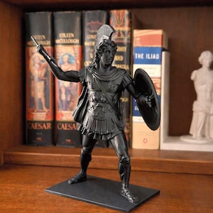 May include: A black statue of a Roman soldier in full armour, including a helmet, shield, and cape. The statue is standing on a black base. The background includes books with titles like "Caesar" and "The Iliad".