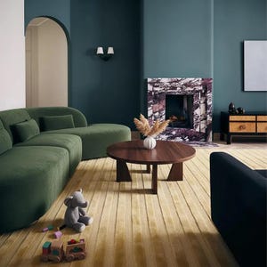 Pu&ograve; includere: Un moderno soggiorno con un divano verde, un tavolino rotondo in legno e un camino in marmo. Un elefante di peluche grigio e un trenino di legno sono sul tappeto giallo. Le pareti sono dipinte di un verde acqua scuro.