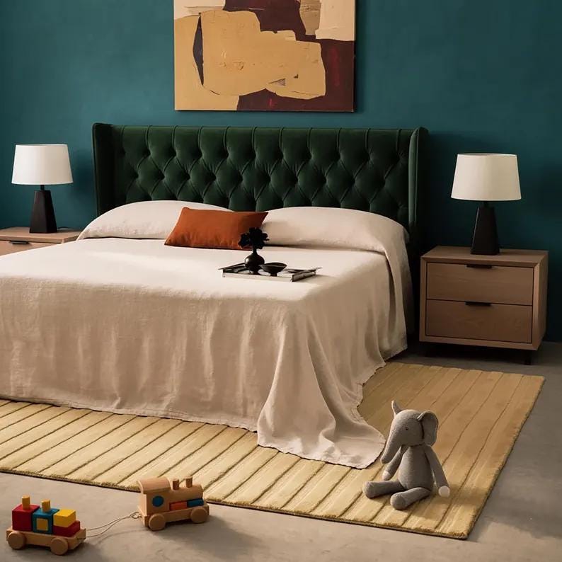 Pu&ograve; includere: Una camera da letto con una testiera verde trapuntata, un letto con una coperta beige e due comodini con lampade. Un cuscino arancione e un vassoio con decorazioni sono sul letto. Un tappeto giallo, un trenino giocattolo e un elefante di peluche sono sul pavimento.