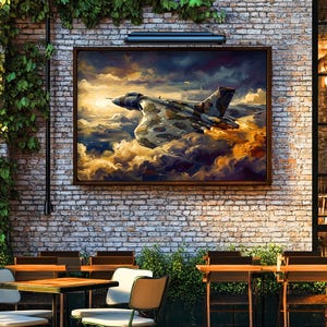 May include: A framed artwork of a military jet in flight, set against a backdrop of clouds and a golden sky. The artwork hangs on a brick wall, above outdoor cafe seating with tables and chairs, creating a rustic ambiance.